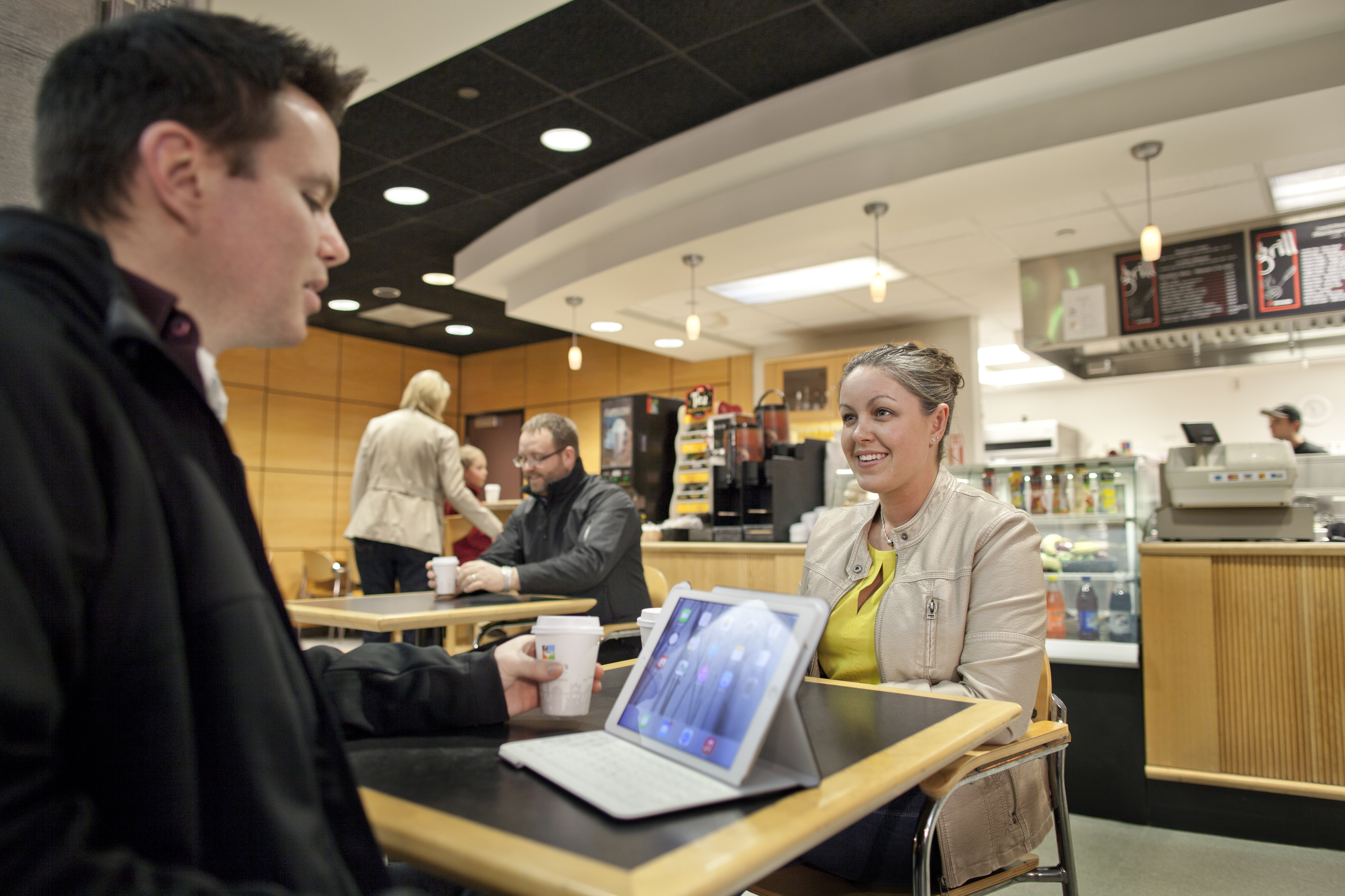Couple sitting at a table with coffee cups and their IPAD inside the terminal